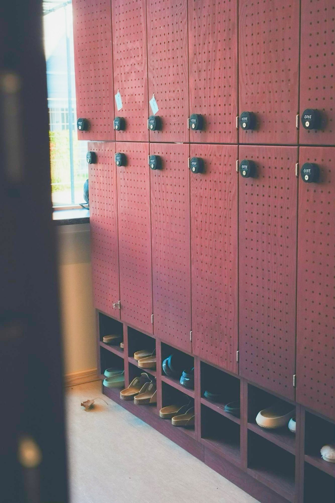 Røde lockers i krydsfiner med perforerede låger, kodelåse og skohylder på Mørkhøj Skole