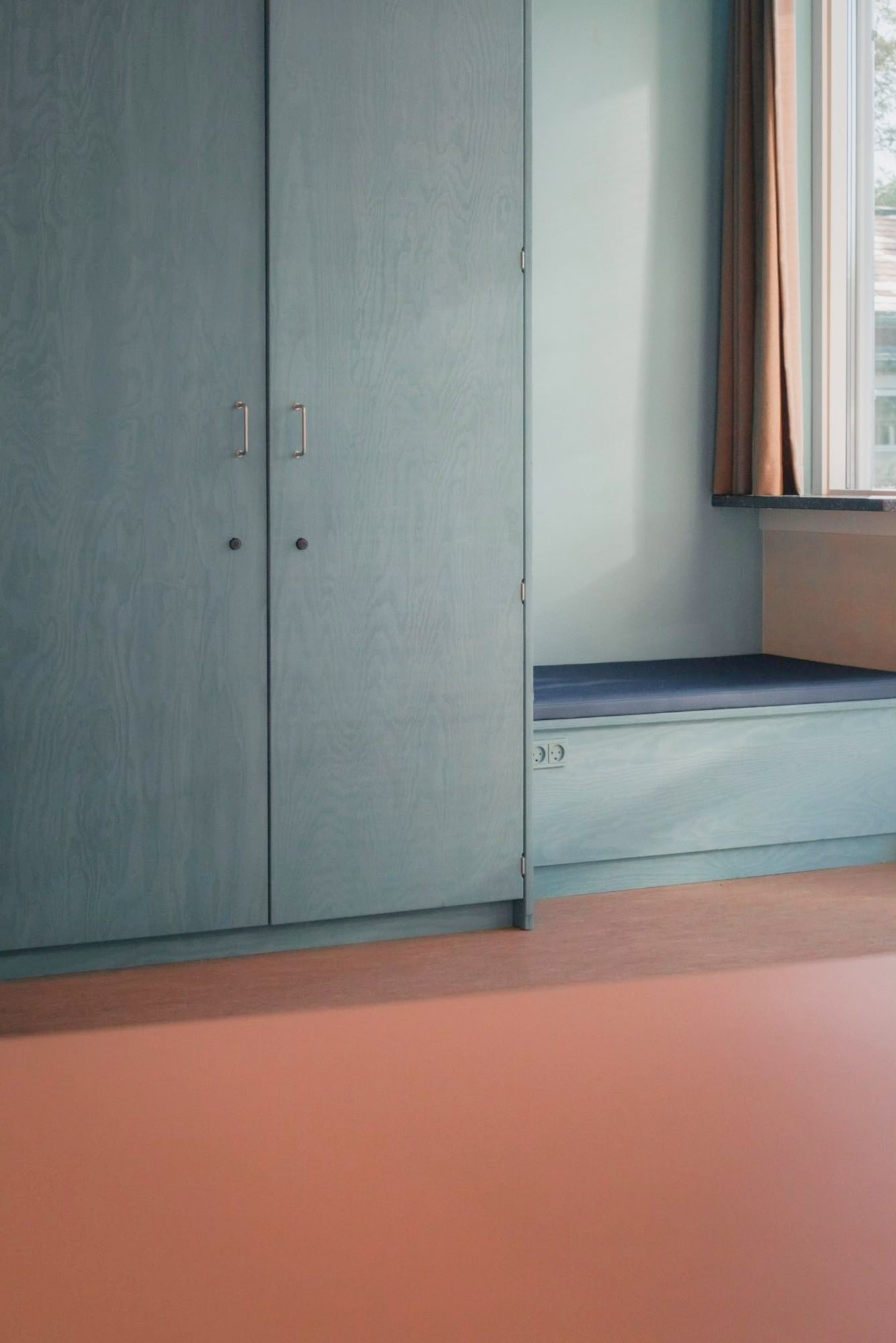 Tall cabinet in plywood and a window seat at Mørkhøj School
